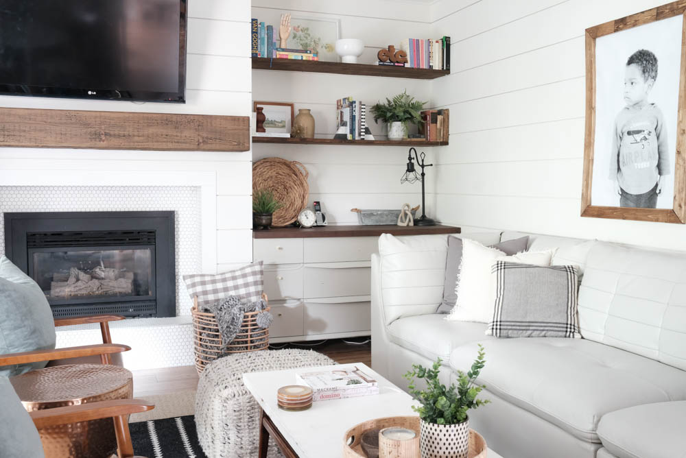 Shiplap living room walls with built-in shelves, a TV and a fireplace