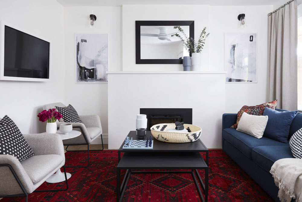 A bright living room with a red rug and a picture-frame TV
