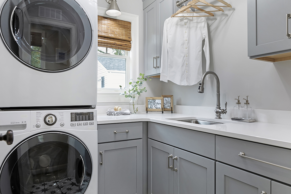 A laundry room with grey cabinetry