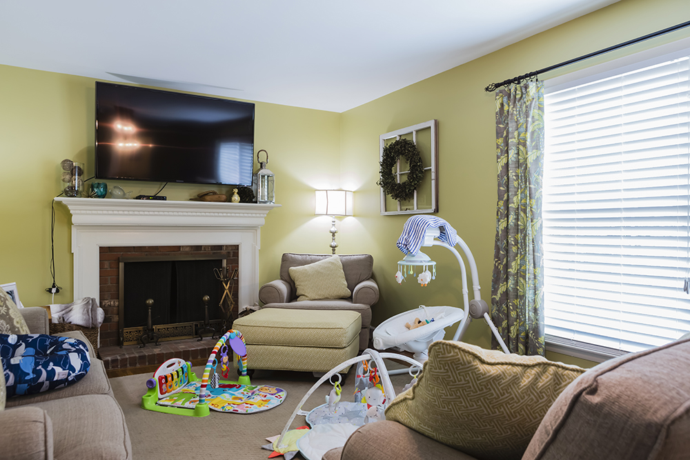 A cluttered family room with baby gear