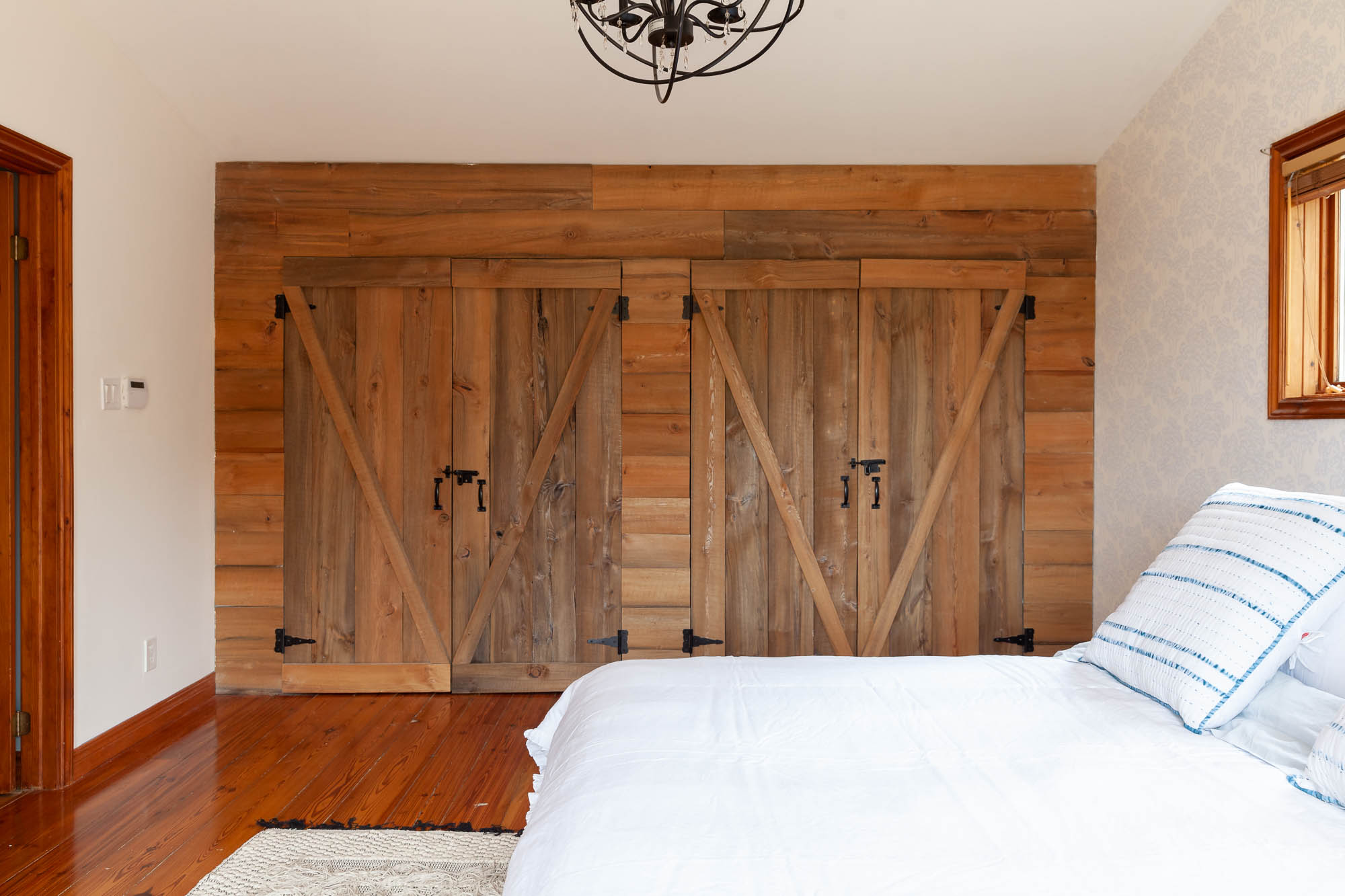 master bedroom with barn doors on closet and reclaimed wood floors