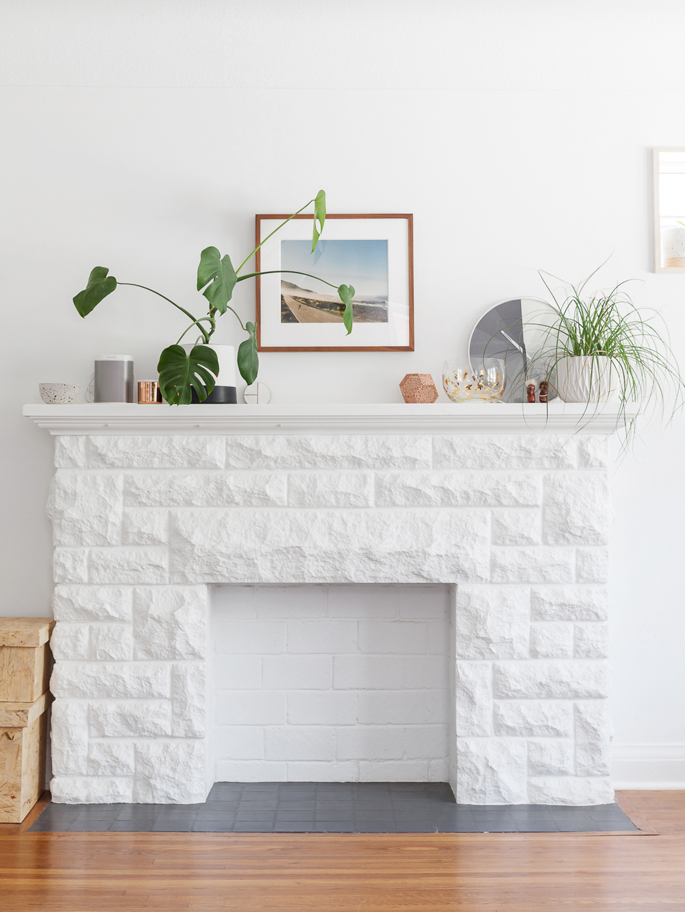 Close-up of the all-white fireplace in the living room with a framed photo hanging above
