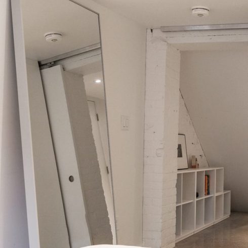 A basement bedroom with a large floor-to-ceiling mirror