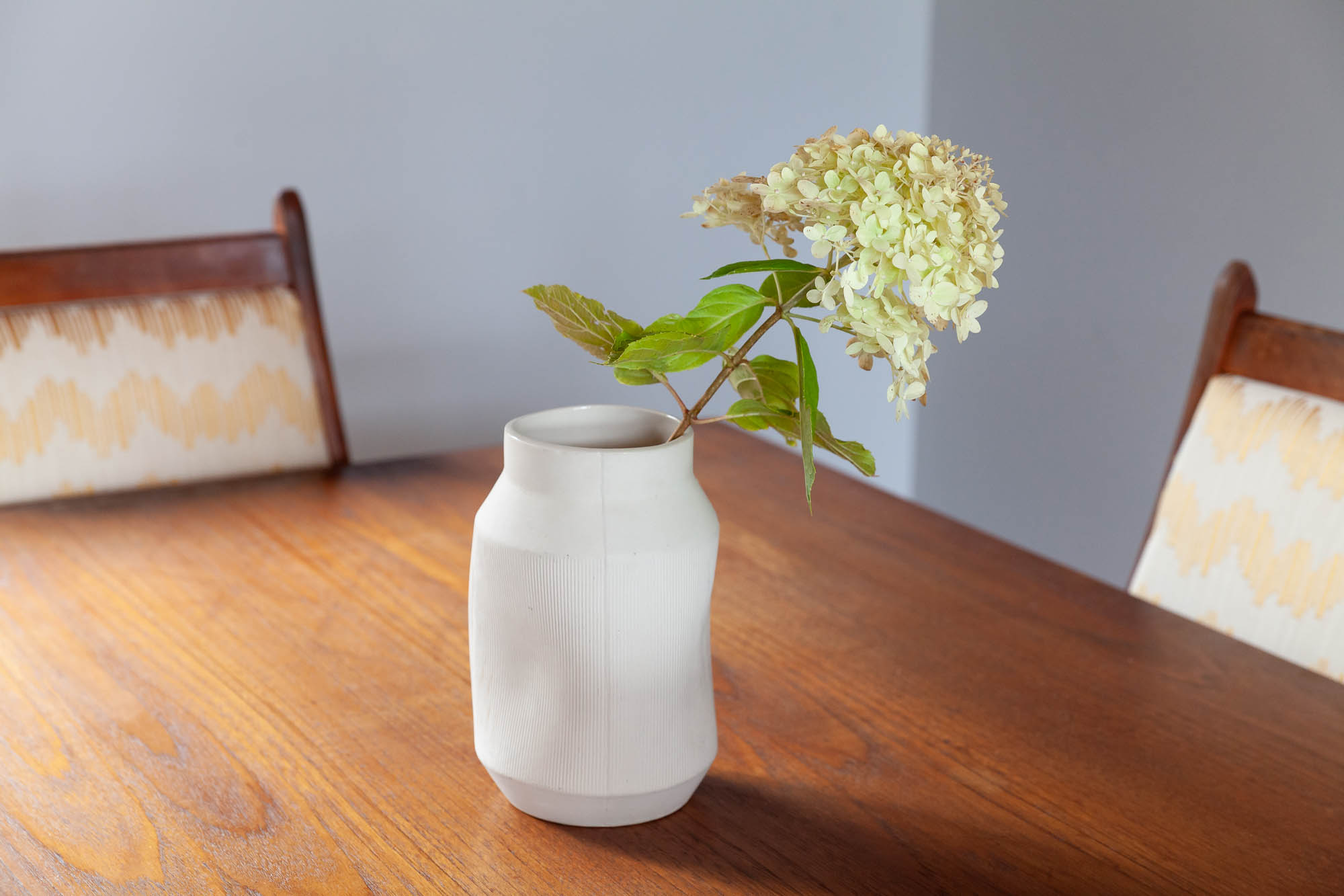 flower in a vase on a vintage teak dining room table