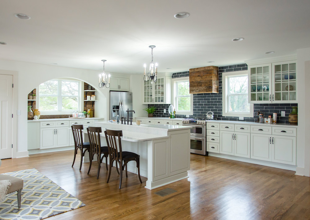 An open-concept kitchen with backsplash, white island and gorgeous archway leading into a little mini pantry.