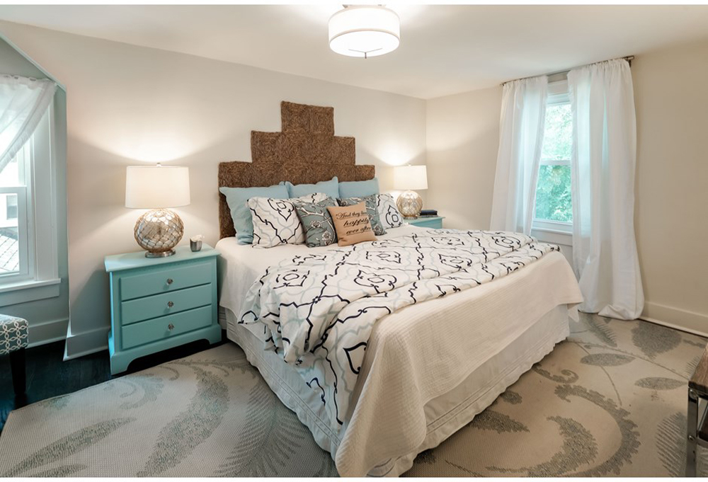 Master bedroom with teal side tables and white drapes