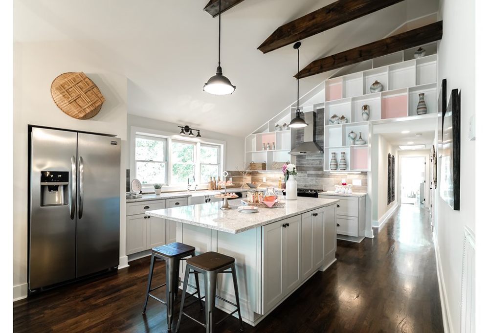 A unique kitchen space with a sloping roof and hints of pink accents on the wall.