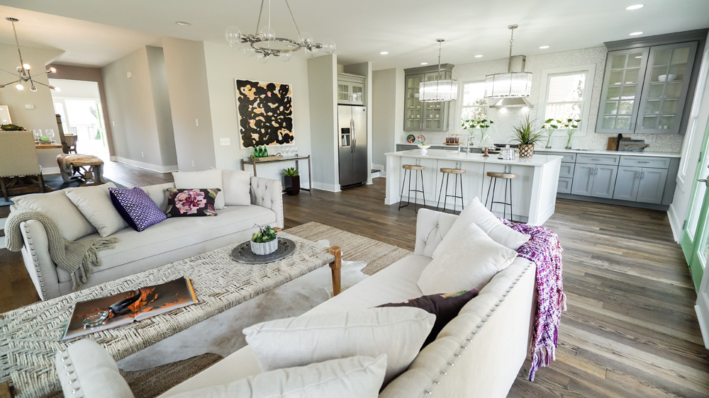 An open-concept living room and kitchen with neutral tones with various pops of colour.