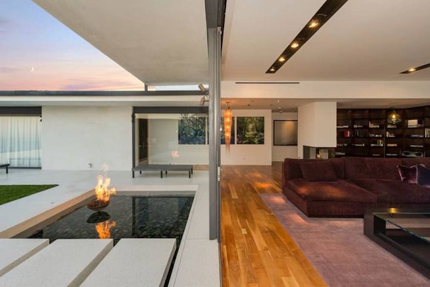 Fire pit and pool area separated by glass wall in living room of Matthew Perry's Hollywood Hills home