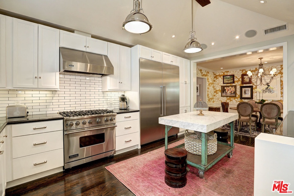 white kitchen with wood floors, pink rug and rolling centre island