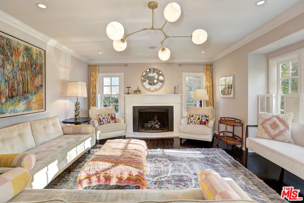 cozy living room with white fireplace, beige couches and a colourful area rug
