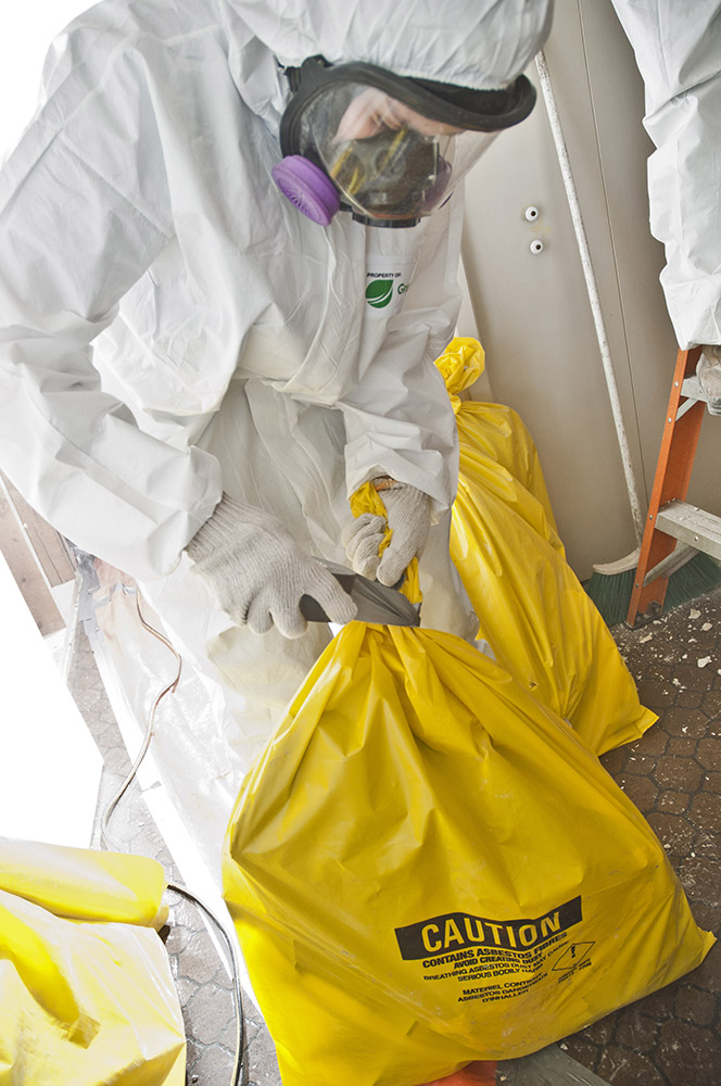 A person in a hazmat suit cleaning up asbestos