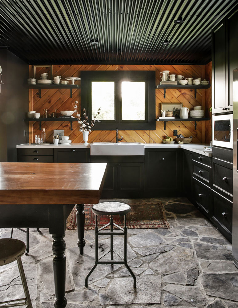 Farmhouse kitchen with corrugated black ceiling and wood backsplash.