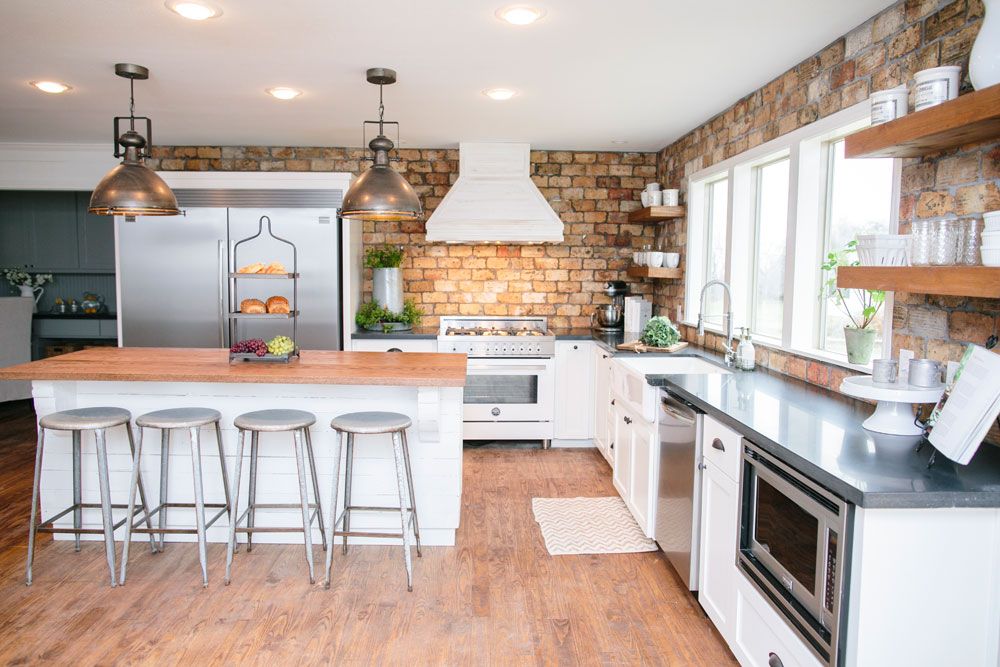 Joanna Gaines farmhouse kitchen design with an abundance of wood and old-school light fixtures.