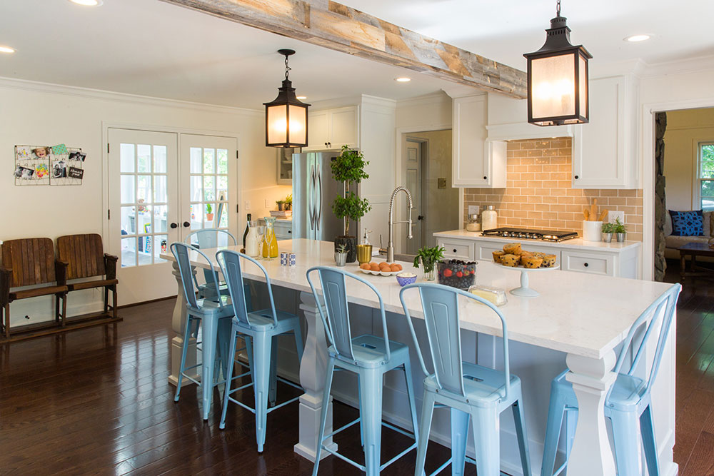 Farmhouse kitchen with rustic island, metal lanterns and raised cabinetry.