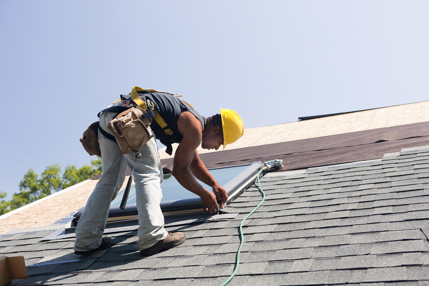 Construction worker installing new shingles on roof