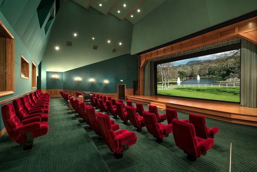 Spacious movie theatre with plush red seats and stage
