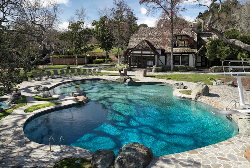 14-foot-deep lagoon-style pool surrounded by a pool house and stone paths