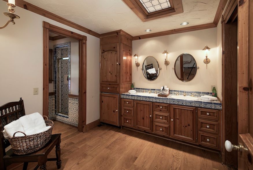 A spacious bathroom featuring wood cabinetry, a dual-sink vanity and a walk-in shower