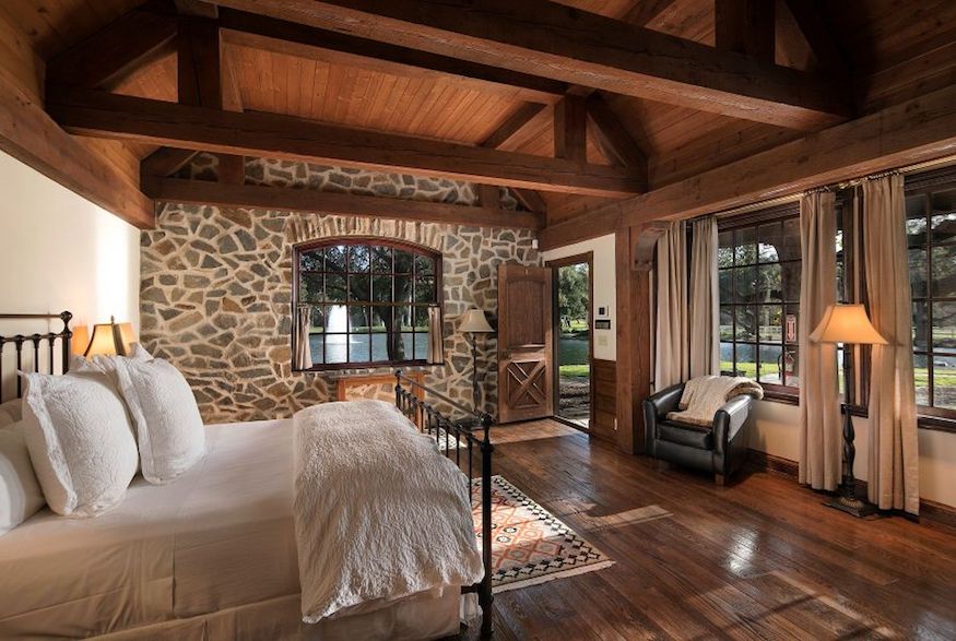 Rustic bedroom featuring wood flooring and castle-like stone walls