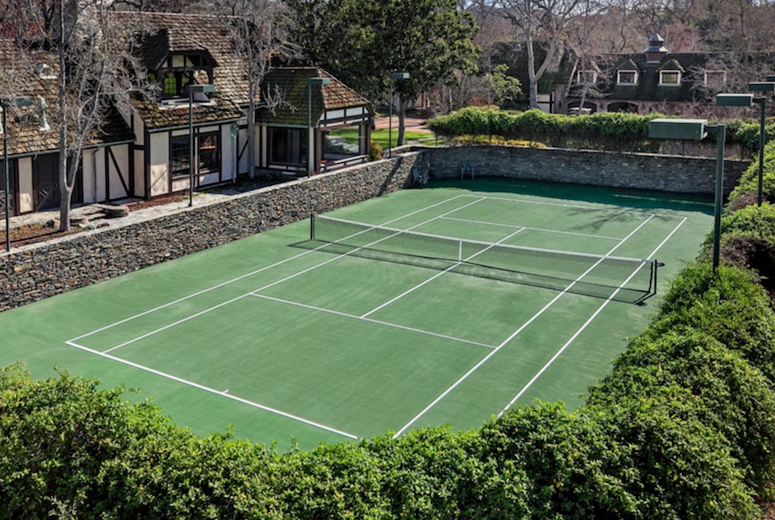A large tennis court surrounded by greenery