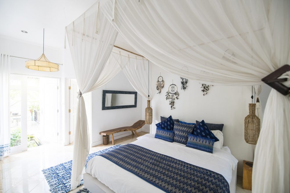 white bedroom with white curtains around bed