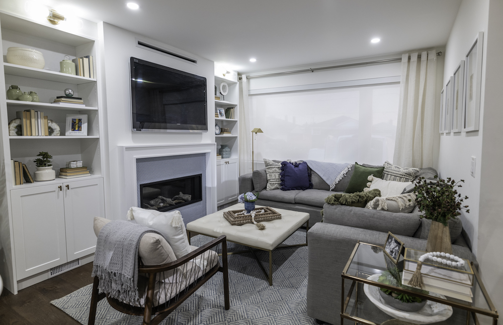 cozy white living room with grey sectional couch and white built-in shelving
