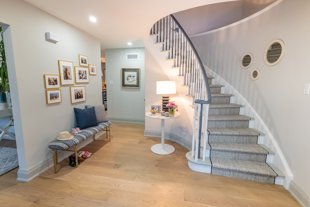 bright front entryway with curved staircase and gallery wall