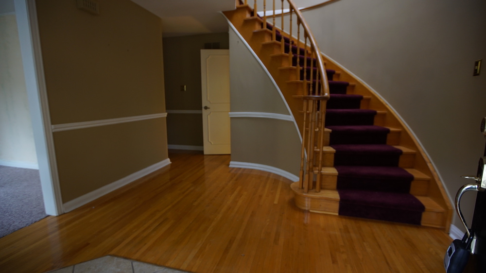 front entryway with curved staircase and dark red runner