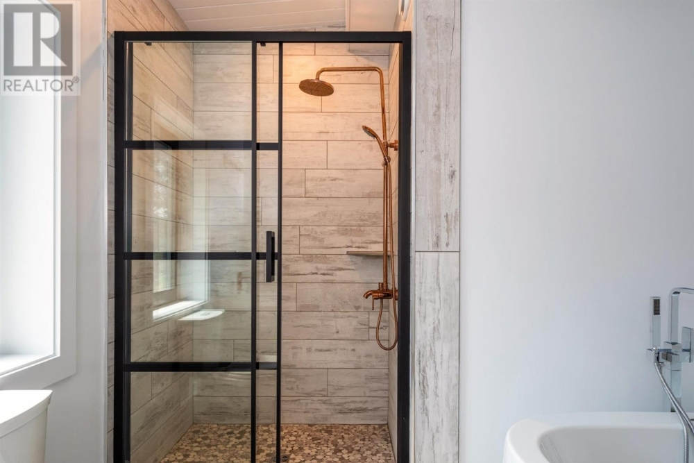 A modern bathroom with black glass shower doors and brass shower fixtures