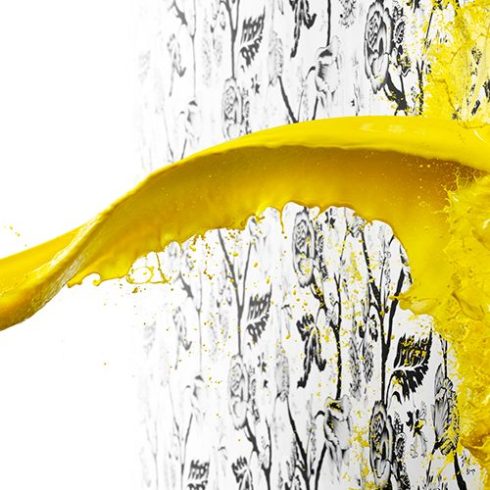 Yellow paint being splashed on a white wall