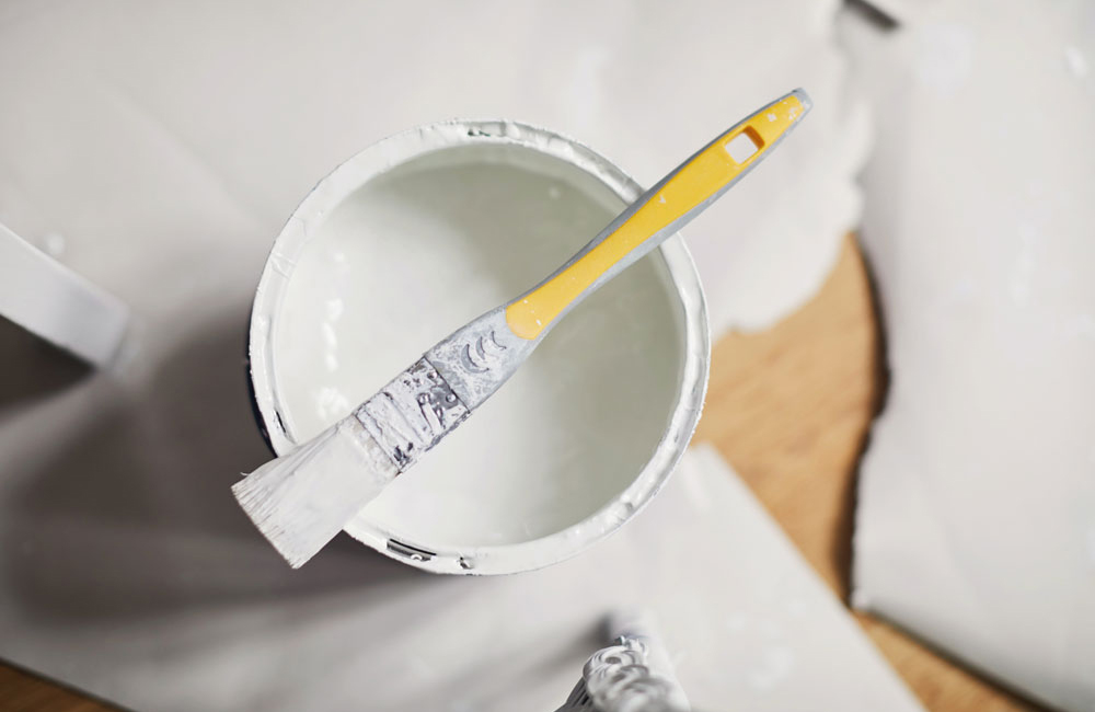 A can of white paint with paintbrush