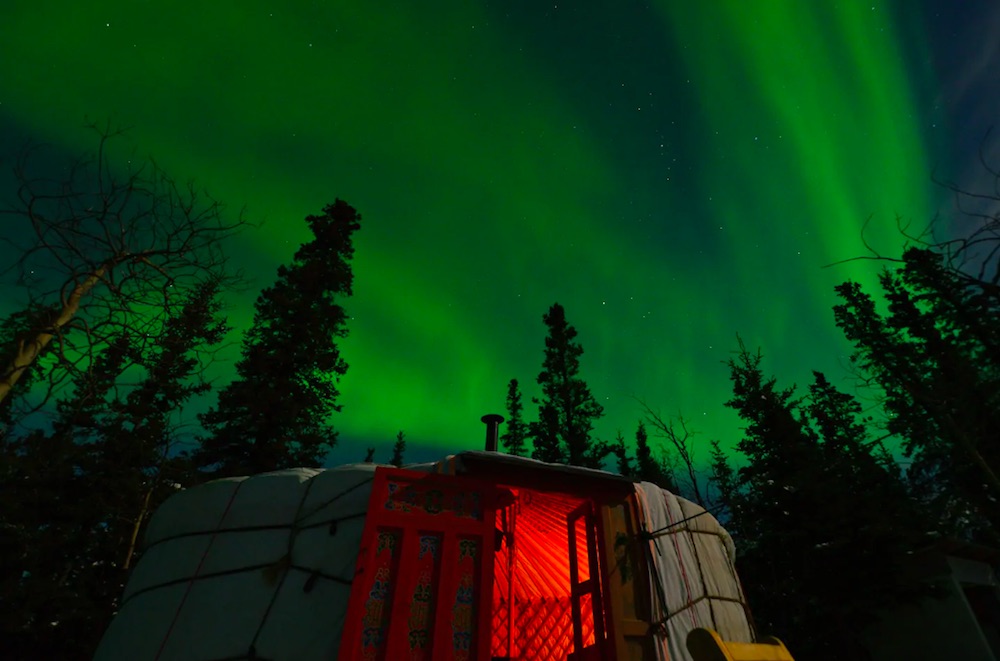 Exterior of Yukon yurt beneath northern lights
