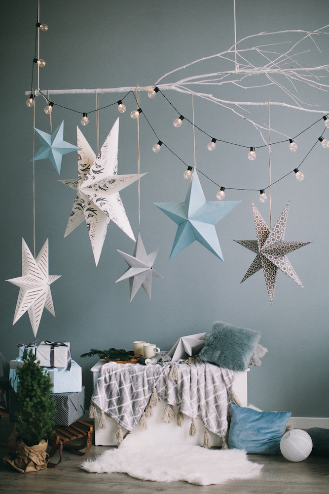 blue room with blue, white and grey hanging stars and lights and presents and pillows on floor
