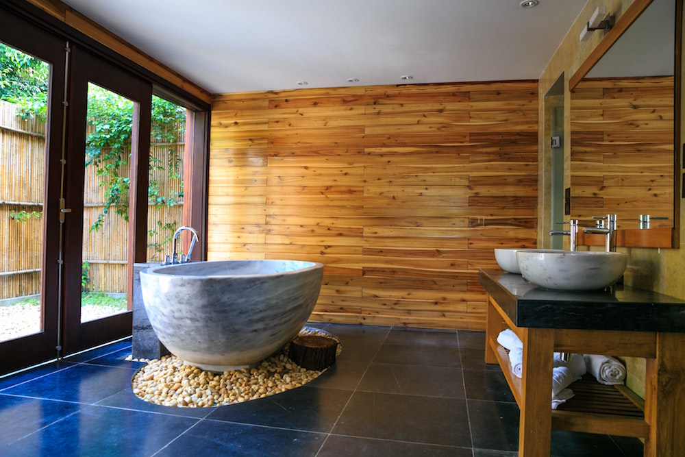 modern bathroom with wood walls, blue floor and grey oval soaking tub