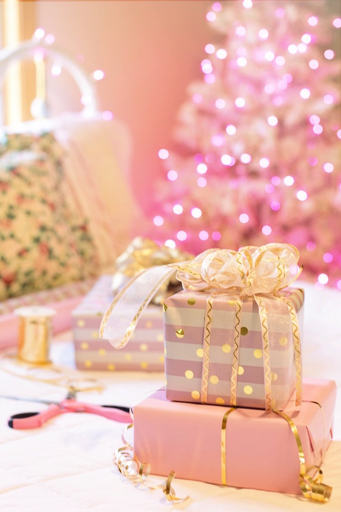 pink wrapped presents on bed in front of pink christmas tree