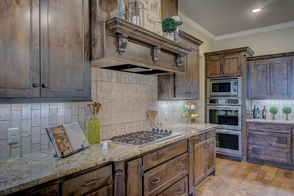 wooden cabinets with ornate hood range in kitchen with granite countertops