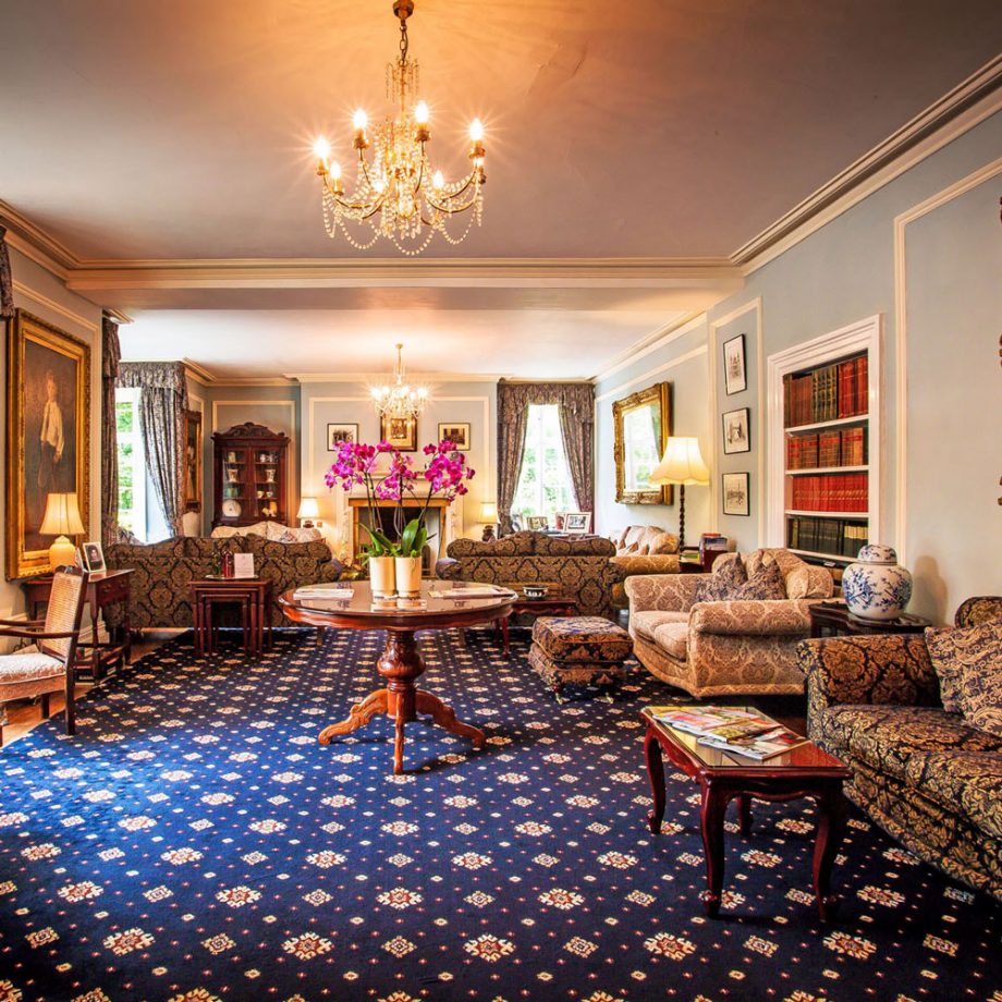 Living room of Plas Dinas, with lush blue patterned carpet, couches and elegant tables and chairs
