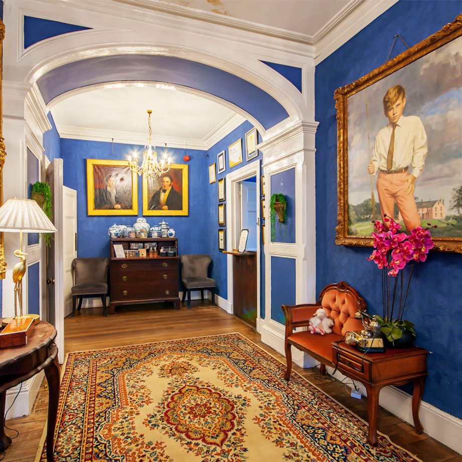 The bright blue hallway inside Plas Dinas with large portraits and mahogany furniture