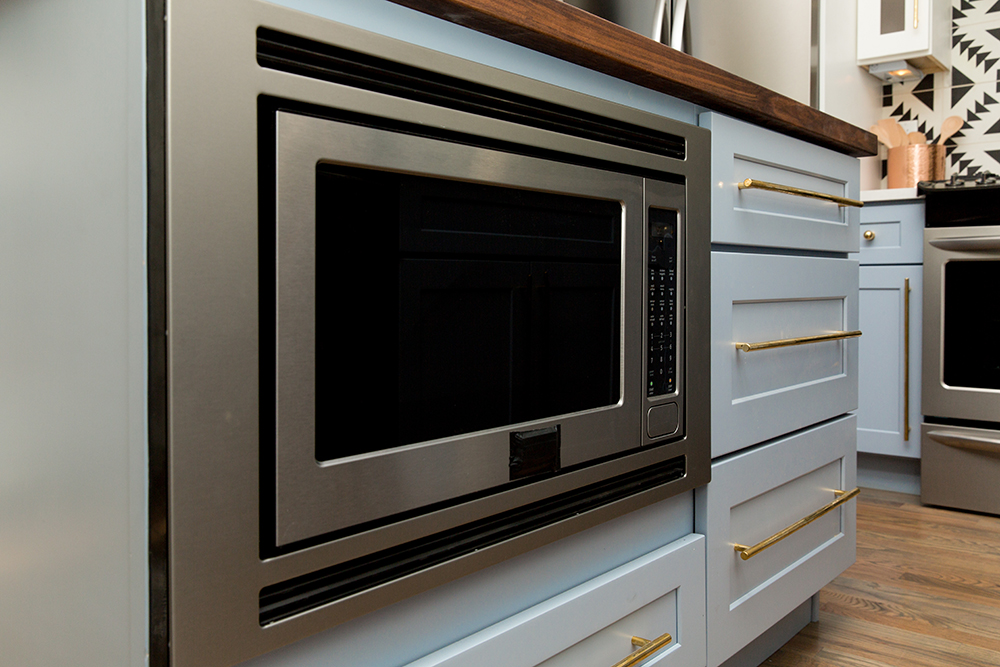Stainless steel appliances in blue kitchen cabinets