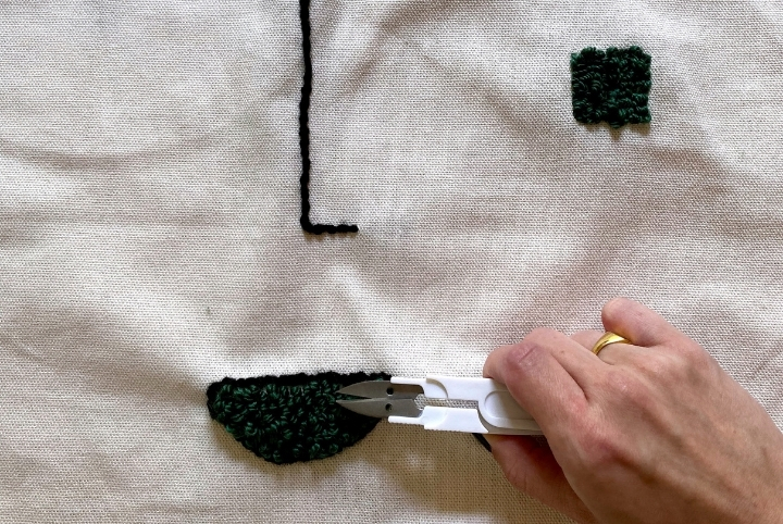Person cutting yarn in a DIY embroidery pillow