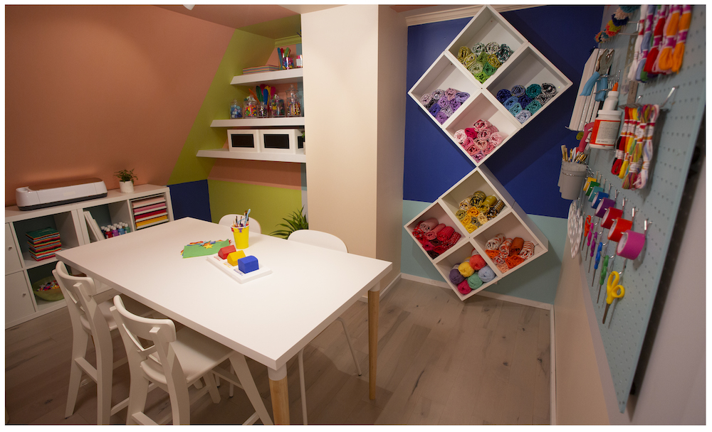 bright and colourful craft room with floating wall shelves and a small table