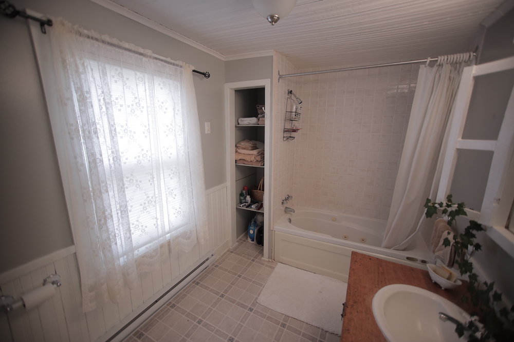 the bathroom before the reno, with white panelling and a large wood vanity