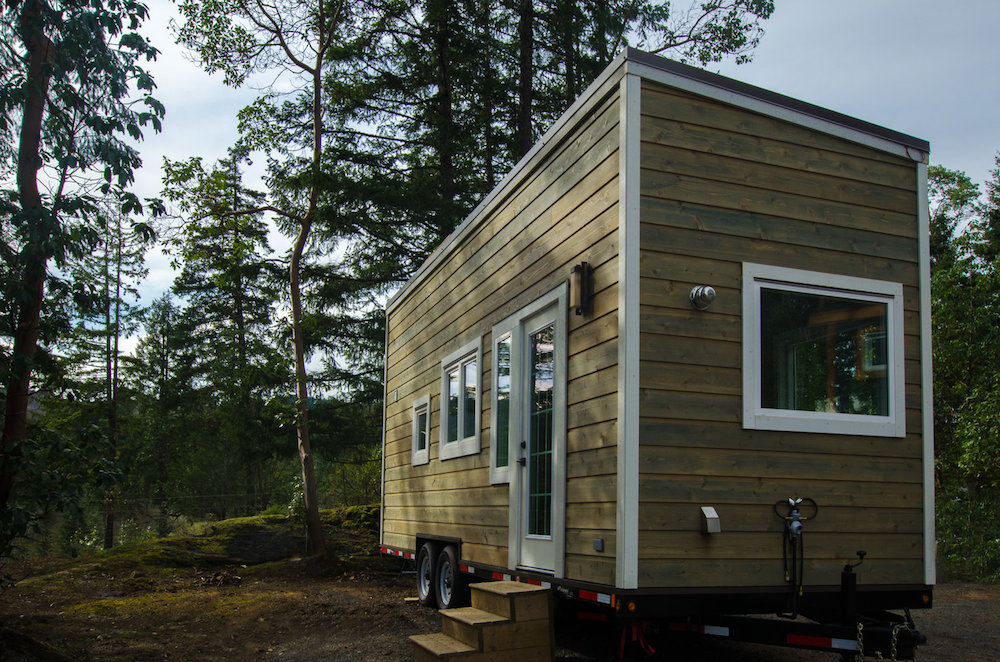 wooden prefab tiny home on wheels in forest