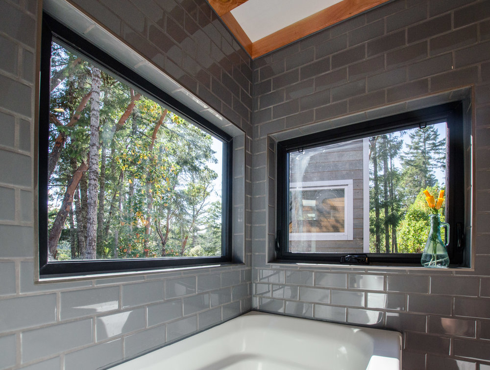 grey tiles in bathroom with windows looking into forest