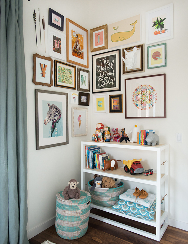 A gallery wall of child prints and images in a corner of a white room