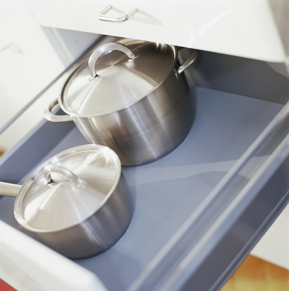 Stainless pots covered with lids in a kitchen drawer