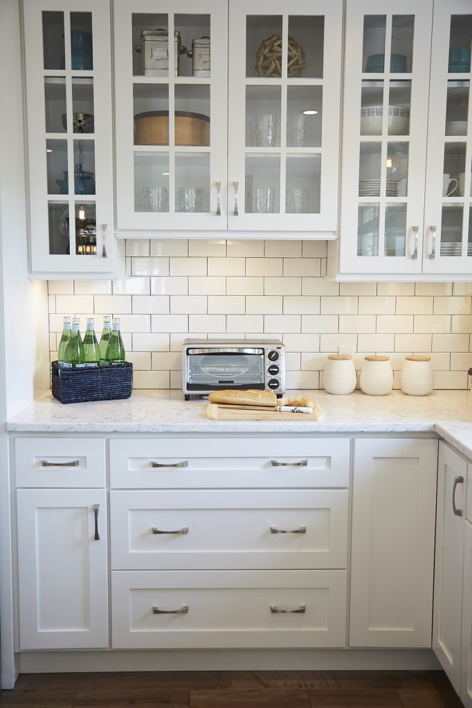 White kitchen with glass cabinet doors and subway tile backsplash