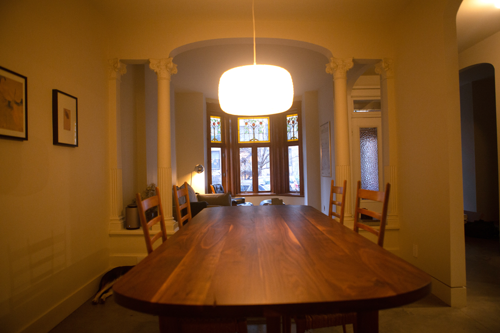 dining room with white pendant light and living room with stained glass windows behind it