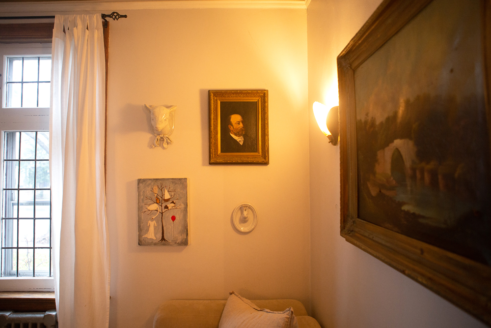 corner of white living room with a mix of paintings and wall sculptures